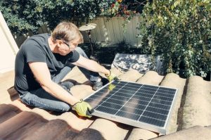 man installing solar panels on the roof during daytime